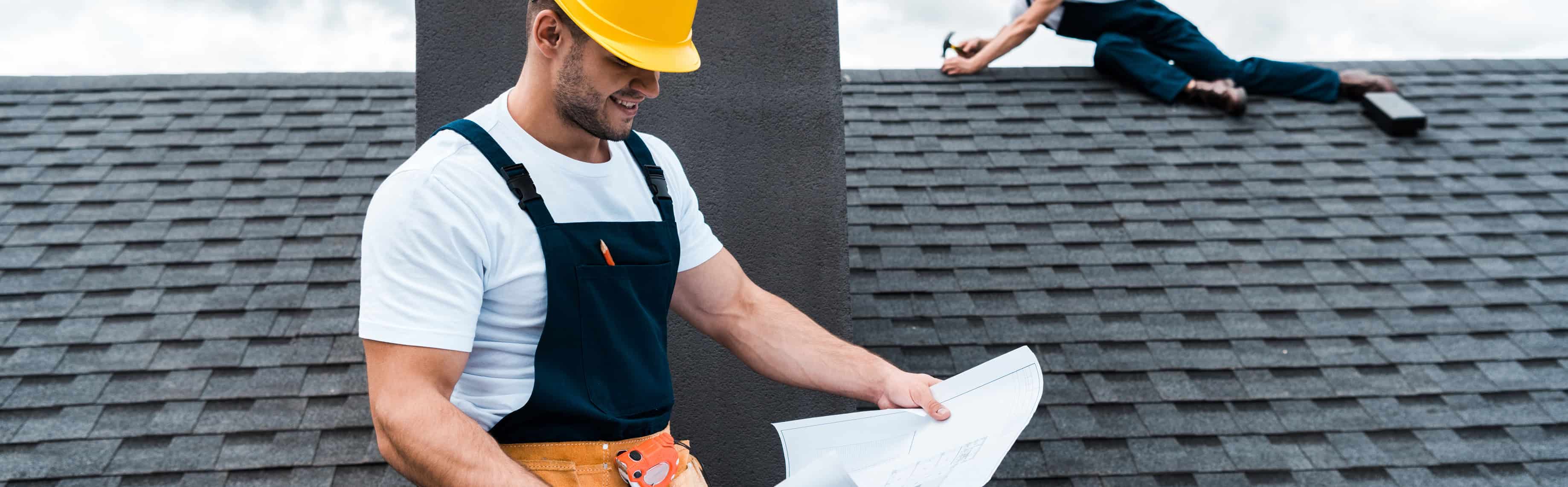 Travailleurs sur le toit avec casques et plans.